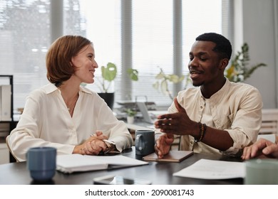 African businessman talking to young businesswoman at the table during a meeting at office - Shutterstock ID 2090081743