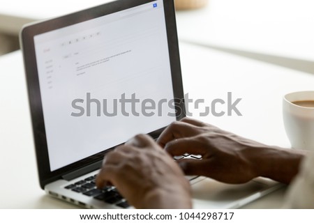 African businessman typing e-mail on laptop using online application pc software, black man mailing client writing e letter on computer screen, business correspondence concept, close up rear view