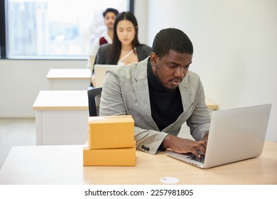African businessman using laptop computer and checking parcel cardboard boxes from online shopping in the office - Shutterstock ID 2257981805