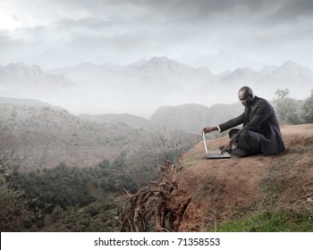 Afrikanischer Geschäftsmann mit einem Laptop auf dem Berg