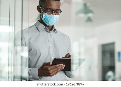 African businessman wearing a face mask using a digital tablet - Powered by Shutterstock