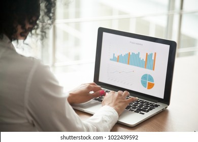 African Businesswoman Analyzing Statistics On Laptop Screen, Working With Financial Graphs Charts Online, Using Business Software For Data Analysis And Project Management Concept, Rear Close Up View