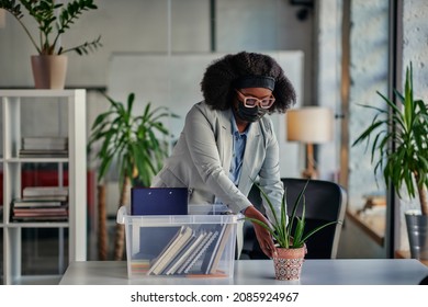 African Businesswoman With Protective Face Mask Return To Work And Setting The Table In Her Office, Taking Out Supplies From Plastic Box