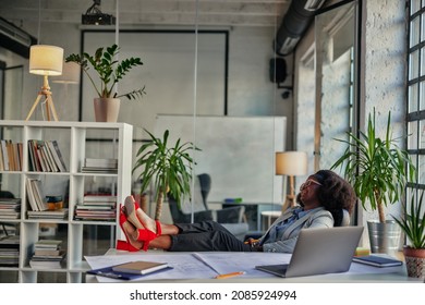 African Businesswoman Relaxing With Legs Up On Desk While Working In Office