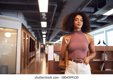 African businesswoman standing with arms crossed smiling to camera in casual office