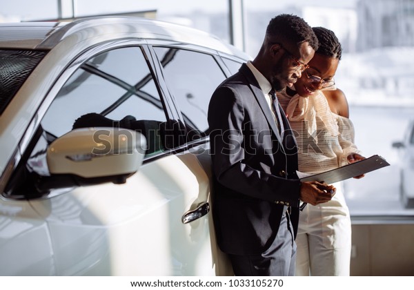 african Car\
dealer showing vehicle to black\
woman
