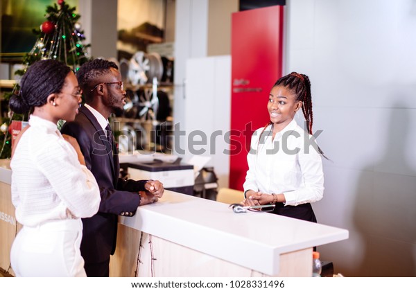 african Car rental assistant giving information\
to couple customer