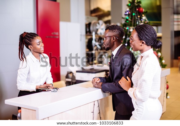 african Car rental assistant giving information\
to couple customer