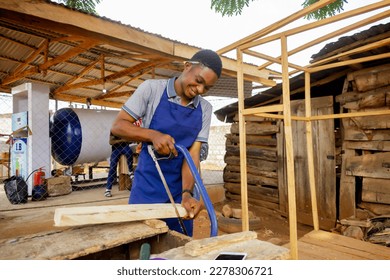 african carpenter holding a tape wearing apron working cutting sawing