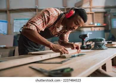 African carpenter measuring wood and timber with electric tools - Powered by Shutterstock