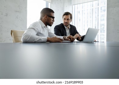 African and Caucasian business partners participate in meeting in modern office, sit at desk with laptop, discussing collaborative project, corporate task, working at boardroom. Teamwork, tech concept - Powered by Shutterstock