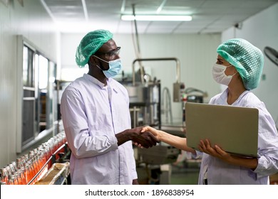 African And Caucasian Lab Specialist Shake Hand For Cooperation In Quality Assurance Of Production In Beverage Industry With Labtop Check List