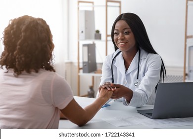 African Cheerful Female Doctor Holding Patient Hand, Consultation At Clinic