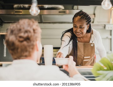 African chef woman serving take away order inside food truck - Focus on senior woman face - Powered by Shutterstock