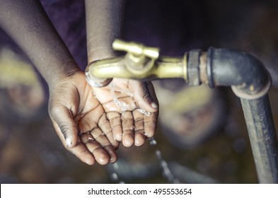 African Child with Hands Cupped under Water Tap in Bamako