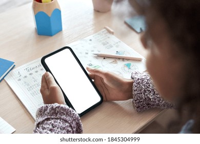 African Child Kid Girl Holding Phone Distance Learning Class Using Mobile Tech, Watching Online Tutoring Video Lesson In App Studying At Home School Classroom, Over Shoulder Mock Up Screen Ads View.