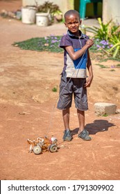 african child playing with a home-made wire car mad out of beer cans