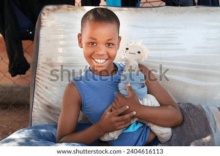 african child in the village, playing with a cloth doll outdoors in the yard