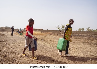 African children fetching water from a village pump; lack of houshold taps and child labour in developing countries