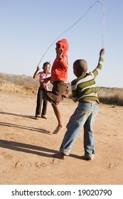 african children jumping rope in the sand, Mmankodi village Botswana