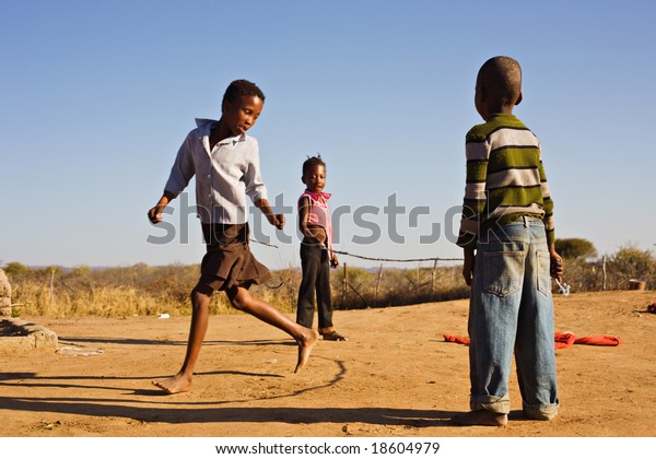 african children jumping rope in the sand, Mmankodi village Botswana