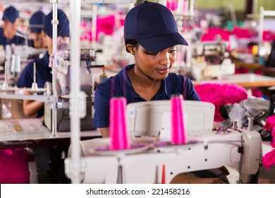 African Clothing Factory Worker Sewing With Colleagues On Background