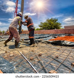 african construction workers in town at the construction site using a boom concrete pump to fill the foundation of a building - Powered by Shutterstock