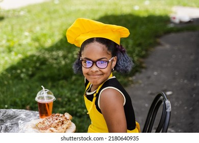 African Cook Child Girl Sin Chefs Hat And Yellow Apron Uniform Smiling Outdoor