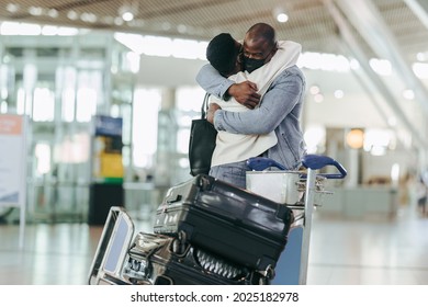 African Couple Giving Each Other A Warm Hug At Airport Arrivals. Young Man And Woman Meeting At Airport During Pandemic.