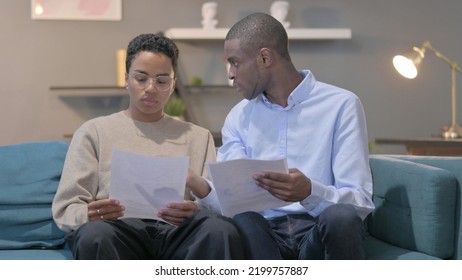 African Couple Reading Documents Together On Sofa