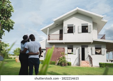 African couple standing back at the front of house and enjoy to talking together, they are talking with each other and look at the house in the garden feeling happy and smile.