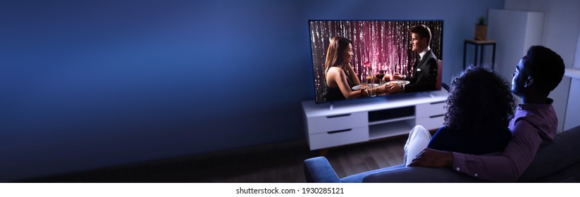 African Couple Watching TV Movie On Television Screen Online