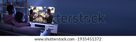 African Couple Watching TV Movie On Television Screen Online