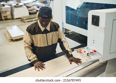 African Craftsman In Protective Headphones And Uniform Concentrating On His Wood Work At Machine