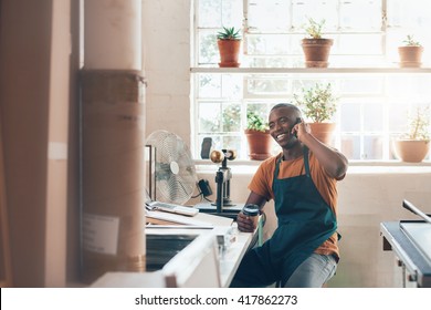 African Craftsman, Small Business Owner Laughing On Phone In Studio