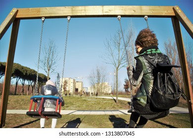 African Creole Mom And Daughter On The Swing At The Playground