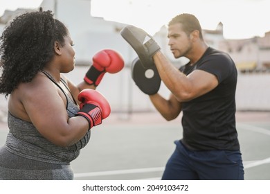 African curvy woman and personal trainer doing boxing workout session outdoor - Focus on girl hand - Powered by Shutterstock