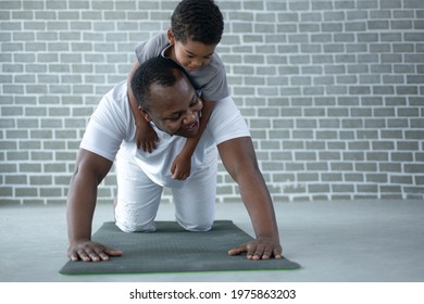 African Dad And Son Exercise On Floor At Home, Man Pushup From The Floor With The Boy On His Back, Father's Day