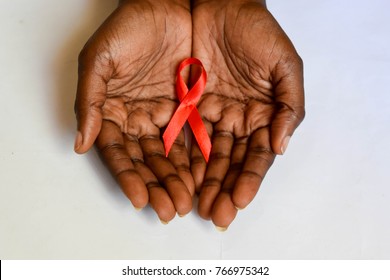 African dark brown skin cupped hands holding red ribbon for HIV AIDS