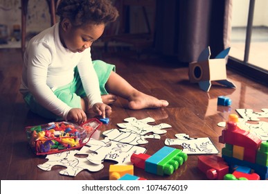 African descent kid enjoying puzzles on wooden floor