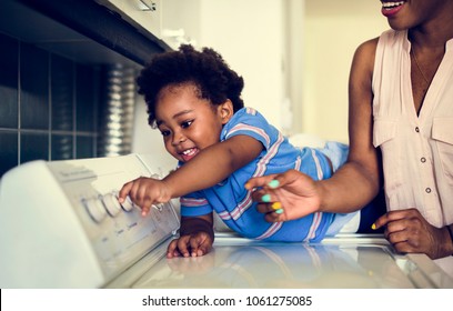 African Descent Kid Helping Mom Doing The Laundry