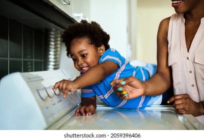 African Descent Kid Helping Mom Doing The Laundry