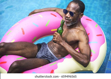 African Descent Man Floating In The Swimming Pool By Inflatable