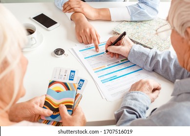 African Descent Woman Travel Agent At Office Pointing At Document For Senior Couple Fulfill Insurance Form Close-up