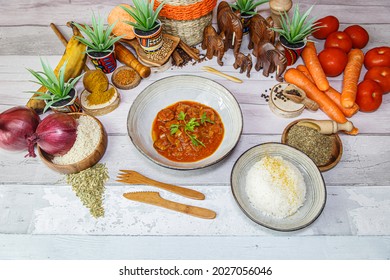 African dish : rougail Sausage with rice. Served on a wooden bowl with food decoration. African menu with starter food, main dish, drink and dessert.