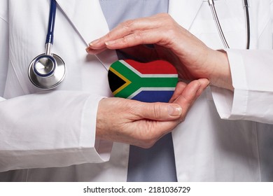 African Doctor Holding Heart With Flag Of South African Republic Background. Healthcare, Charity, Insurance And Medicine Concept