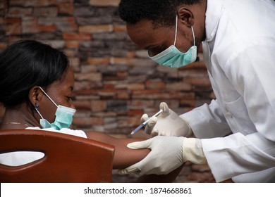 African Doctor Injecting An African Woman With A Vaccine For Covid 19