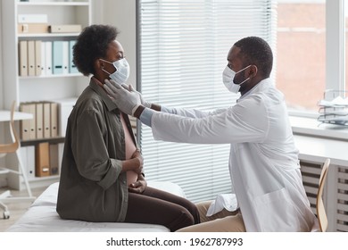 African Doctor In Protective Mask Examining Pregnant Woman During Her Visit At Doctor's Office