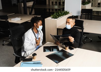 African Doctor Show X-ray Asian Patient. Black Surgeon Analyzing X Ray And Diagnosis Patient In Medical Clinic