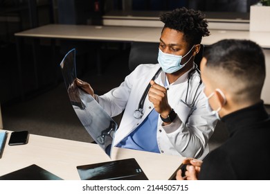 African Doctor Show X-ray Asian Patient. Black Surgeon Analyzing X Ray And Diagnosis Patient In Medical Clinic